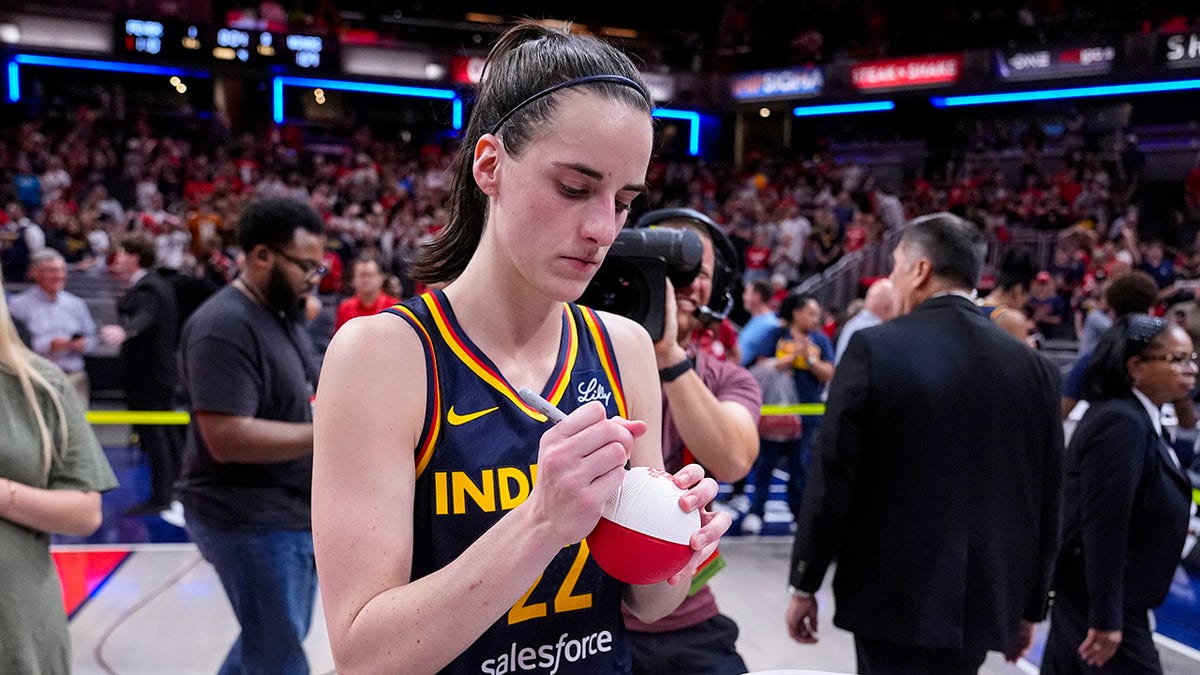 Caitlin Clark signs a ball