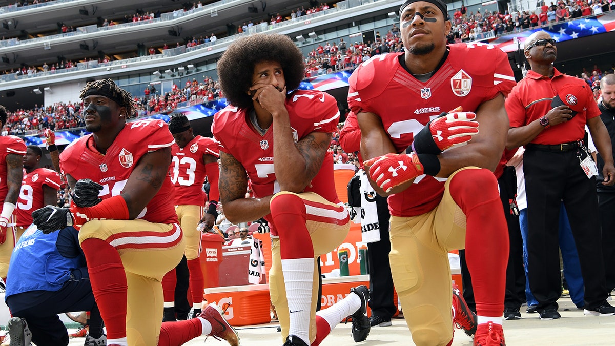 Colin Kaepernick in 2016 kneeling on sideline with other SF 49ers